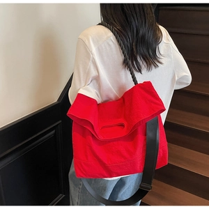 Detail view of large red tote bag with black rope handles and adjustable nylon strap