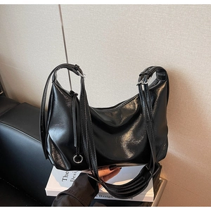 Detail of glossy black moon bag with adjustable straps and metallic hardware accents