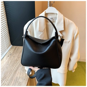 Close-up of black lychee grain leather handbag with round handle and metal hardware