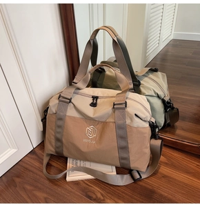 Detail of travel bag showing dual-tone beige design and reinforced handles on wood floor