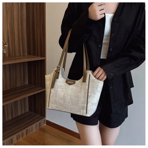 Detail of canvas tote bag with brown leather trim and JINGPIN logo on model shoulder