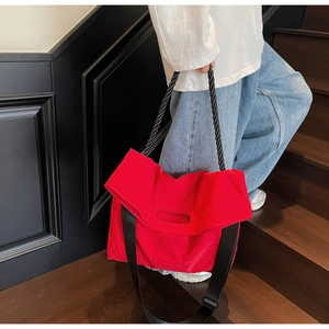 Detail of red large tote bag with wide strap and braided handle on model