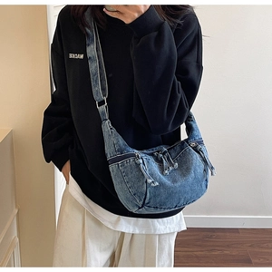Detailed close-up of retro washed denim crescent crossbody bag with silver buckle and frayed trim