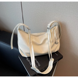 Detail of adjustable straps and metal buckle on cream faux leather hobo tote bag