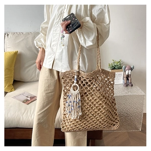 Detail shot of handwoven straw tote bag with decorative tassels and eye charms