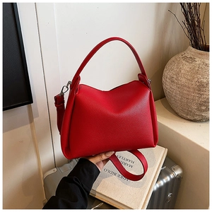 Detail of red lychee textured leather handbag with silver hardware and wide shoulder strap