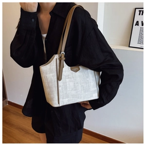 Detail of vintage beige woven tote with brown leather straps and silver buckle