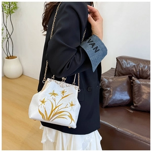Detail of vintage canvas bag with gold floral embroidery and metallic chain strap shown on model