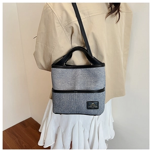 Sac seau en denim bleu avec bandoulières en cuir noir dans une scène de style de vie