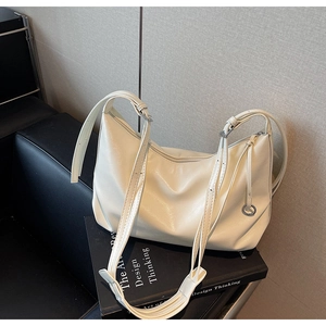 Detail of soft off-white faux leather hobo bag with adjustable silver buckle straps