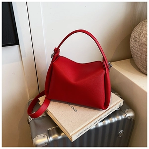 Detailed texture of red litchi grain leather handbag on book with strap detail