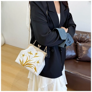 Close-up of a white canvas handbag featuring exquisite yellow lily floral embroidery