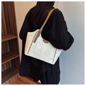 Side view of a woven linen tote bag with brown leather straps shown on a model