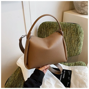 Macro detail of brown pebble grain leather handbag on a green textured chair