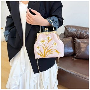 Detail of pink embroidered floral handbag with vintage metal frame and gold chain strap