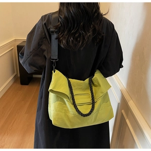 Detail of lime green crossbody bag with black braided handle and wide nylon shoulder strap