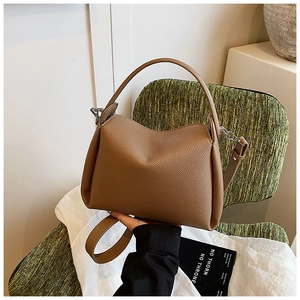 Detail of a brown lychee pattern leather handbag placed on a green vintage chair