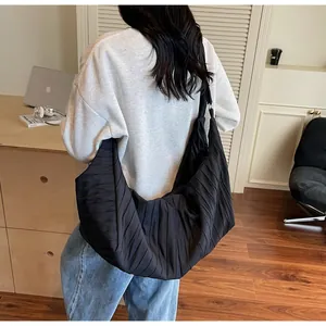 Detail of a large black tote bag with pleated texture worn by a model in a casual setting