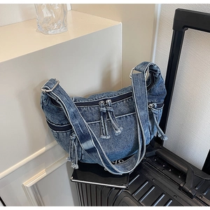 Detailed macro shot of vintage washed denim hobo bag featuring multiple zippers and tassels