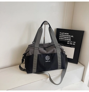 Detail of grey and black nylon travel bag with detachable strap and brand logo