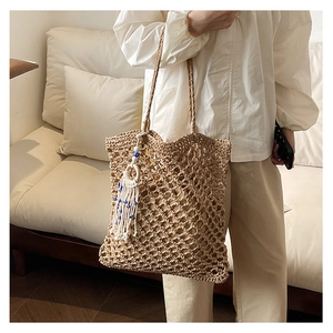Detail of bohemian woven beach tote with white tassels and evil eye charm decoration