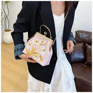 Close-up of pink embroidered canvas handbag with floral patterns and gold chain