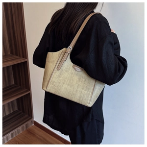 Detailed macro view of khaki woven texture and brown leather trim on the tote bag