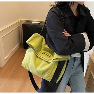 Detail of neon green crossbody bag showing thick black rope handle and wide nylon strap