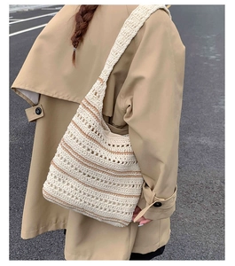 Detail of hand-woven cream and brown striped hobo shoulder bag worn on trench coat
