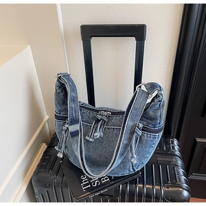 Macro detail of washed denim hobo bag featuring silver zippers and contrast stitching