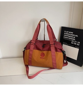 Detail view of large travel bag with red and yellow color block design and adjustable strap