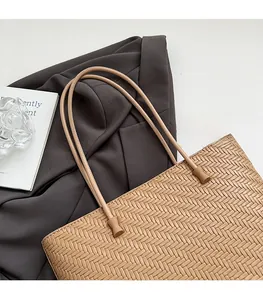 Detail of beige wheat straw woven tote bag showing slender shoulder strap and soft texture