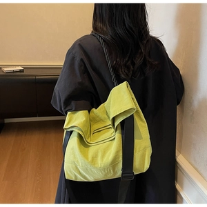 Detail of lime green nylon tote bag featuring black wide strap and double handle design