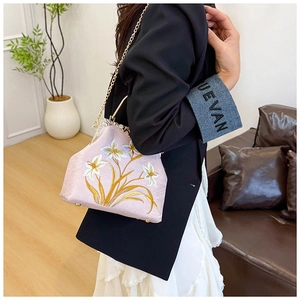 Detail of light pink silk fabric handbag featuring exquisite lily flower embroidery work