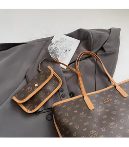 Dettaglio della borsa tote stampata e pochette coordinata su abito grigio con logo