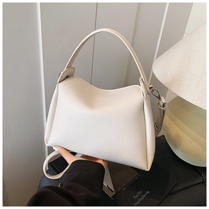 Detail of off-white lychee grain leather texture and silver hardware on small square handbag