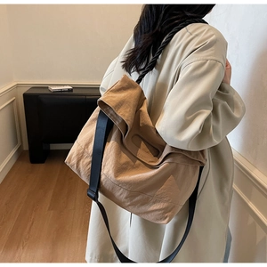 Detail of khaki large capacity crossbody bag with wide black strap and durable nylon texture