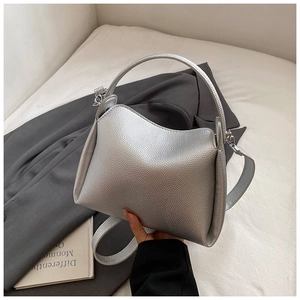 Close-up of a silver litchi grain leather handbag with minimalist top handle design