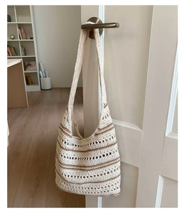 Detail of woven tote bag with brown stripes hanging on a door handle in soft indoor light
