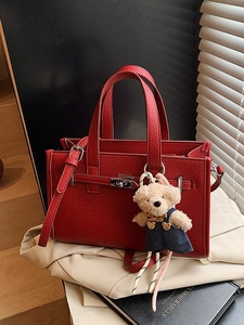 Red litchi-textured handbag with a metal lock and a cute plush bear pendant accessory