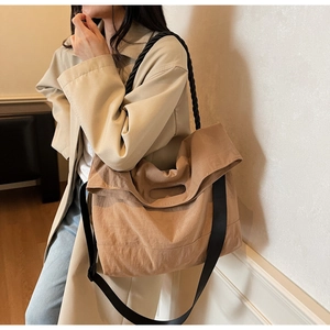 Detail of khaki large tote bag with wide black woven strap and textured fabric