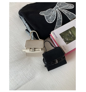 Close-up of mini leather handbags in black and off-white with decorative buckle straps