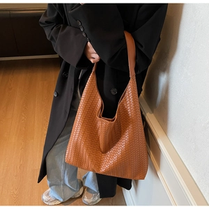 Detail view of large woven leather hobo bag in orange-brown with wide shoulder strap