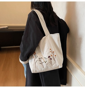 Detailed close-up of white canvas tote bag featuring colorful wildflower embroidery texture