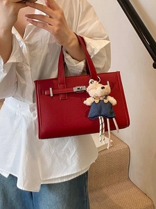 Classic red textured handbag with silver twist lock and cute bear charm in hand