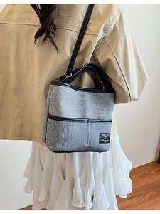Sac seau minimaliste en toile grise avec garniture en cuir noir porté par un modèle chic