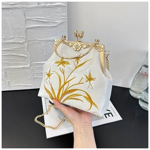 Detail of elegant gold orchid embroidery on ivory silk-textured kiss-lock bag