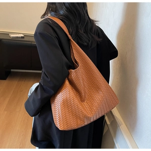 Detailed view of caramel woven leather tote bag texture and over-the-shoulder look
