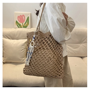 Detail of hollow woven tote bag with beaded tassel charm and large mesh texture