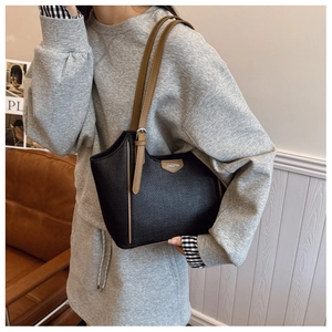Close-up of black woven texture tote bag with brown straps and leather brand tag